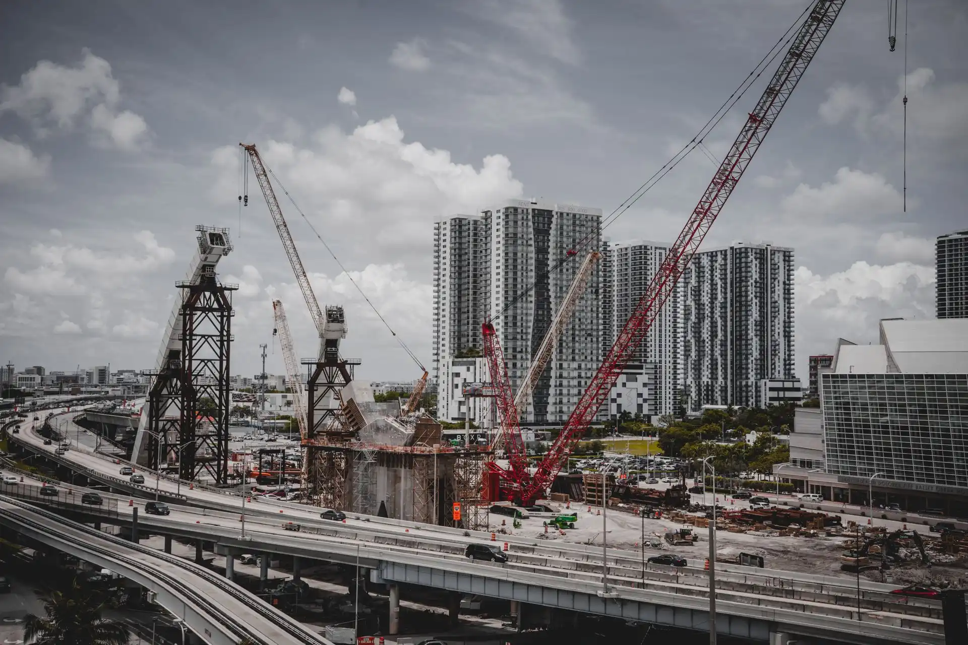 Obra de construcción con grúas torre y edificios en desarrollo bajo un cielo nublado