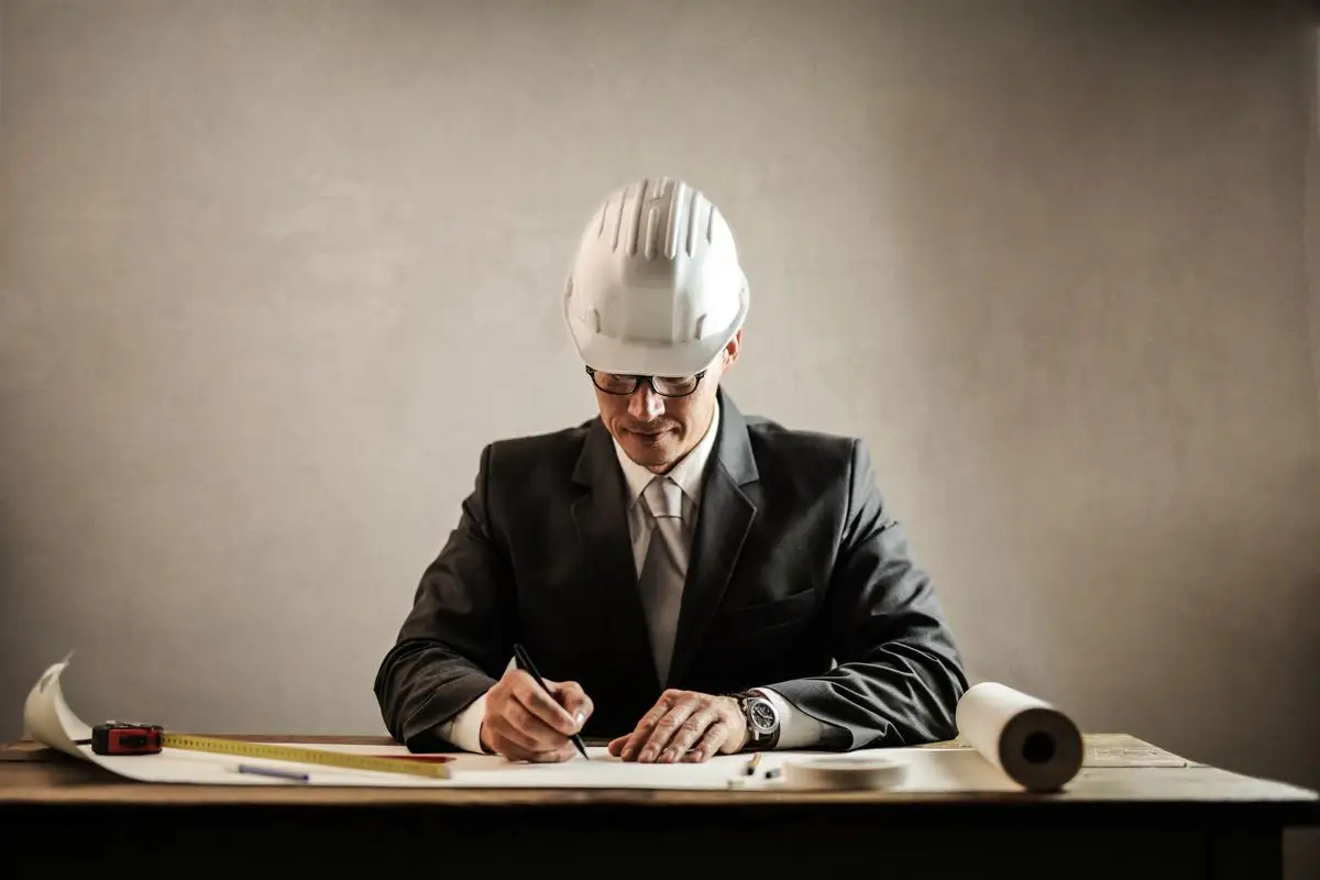 Ingeniero con casco de protección revisa planos técnicos en su escritorio
