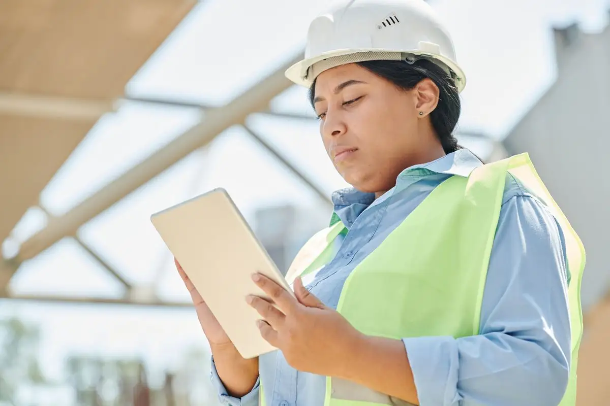 Ingeniera con casco de seguridad supervisa un proyecto con una tableta a pie de obra
